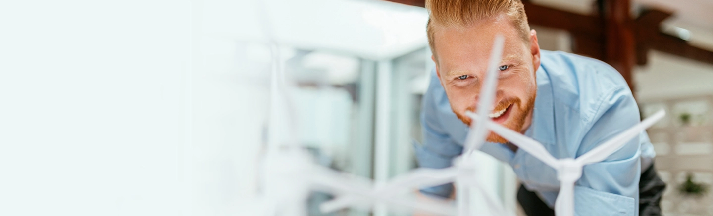 Man smiling and looking at models of wind energy fans