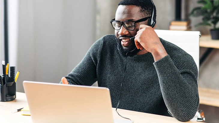 Man working on laptop and wearing and speaking on headset