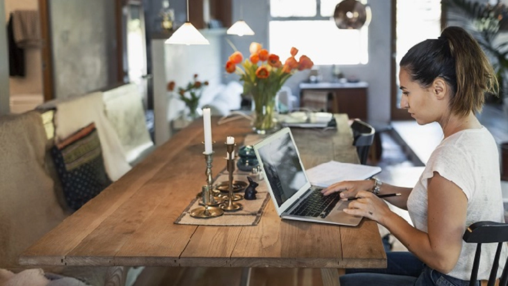 Woman working on laptop on dining room table