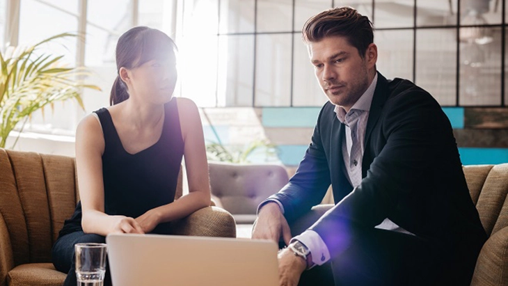 Man and woman sitting in front of an open lap top