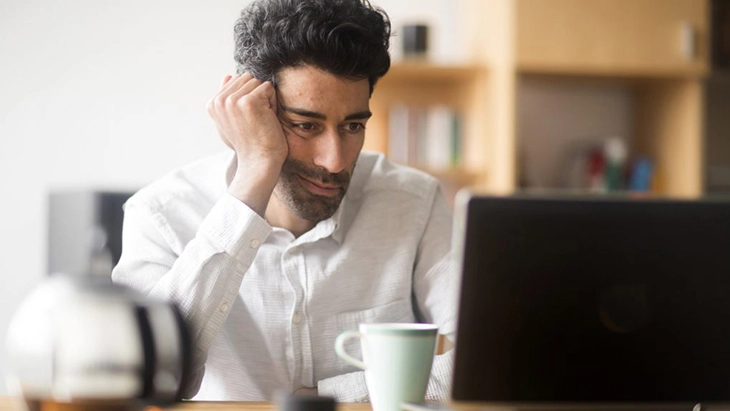 Man working on laptop and leaning head on hand