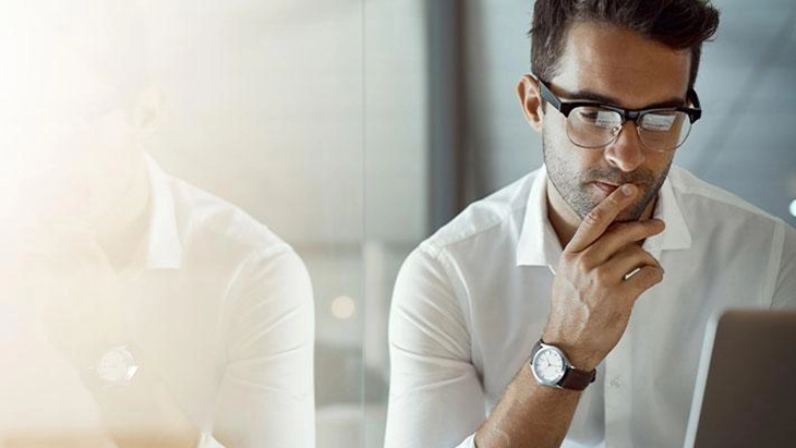 Man with glasses looking at computer screen