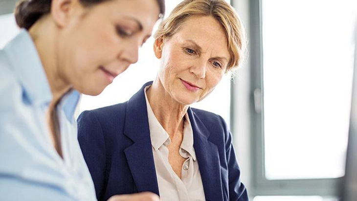 Older woman watching younger woman working